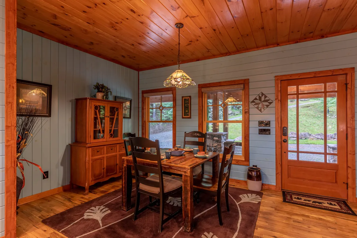 A warm, inviting dining area with a wooden table, elegant chandelier, and large windows. The space is ideal for both festive family feasts and intimate morning coffees, with natural light enhancing the cozy atmosphere.