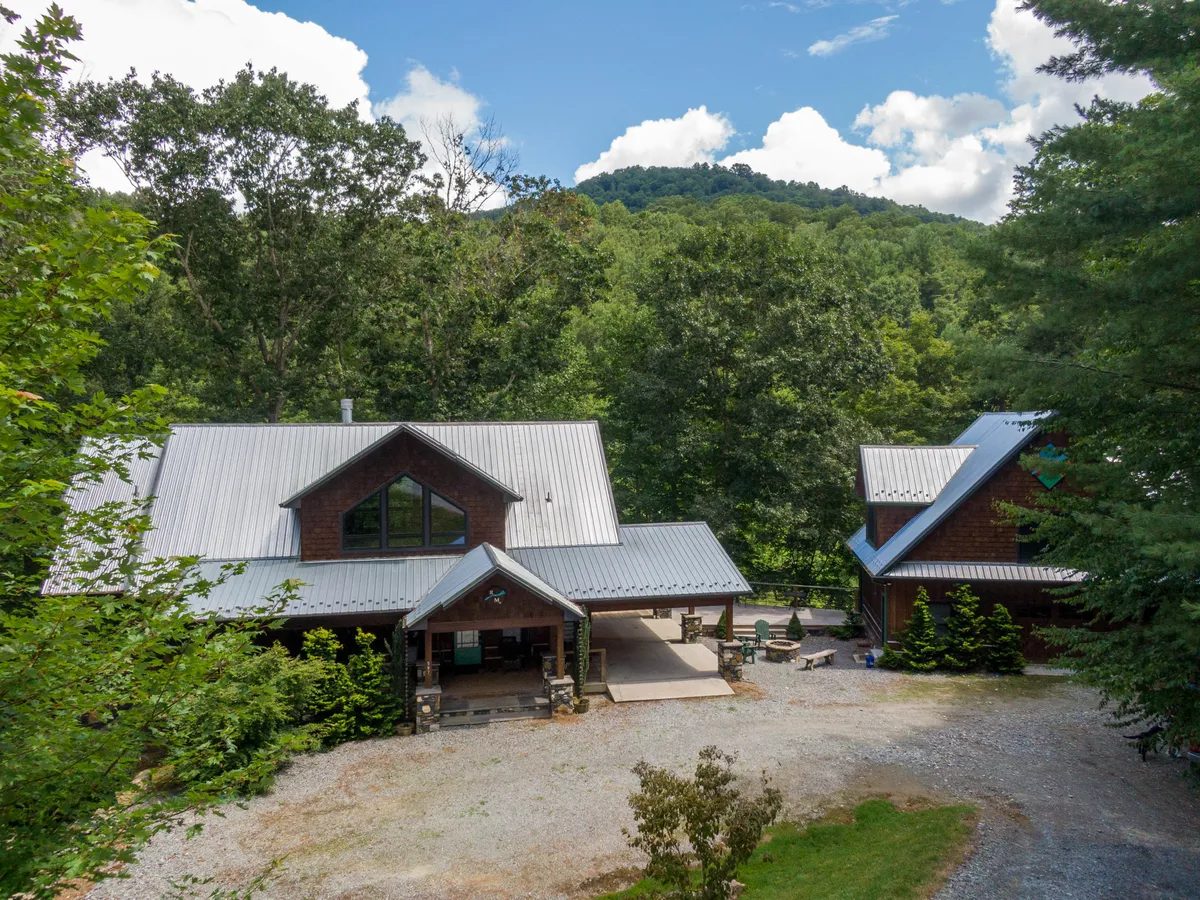 A wide shot of the home’s exterior, surrounded by trees and set against a breathtaking mountain backdrop. The spacious porch invites guests to relax after a day of adventure, while the views hint at the broader outdoor playground available nearby—perfect for year-round mountain activities.